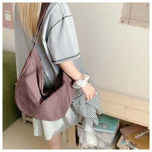 Detail der karierten Nylon-Hobo-Tasche mit breitem Schultergurt in Alltagsszene
