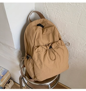 Detail of light brown drawstring backpack with pleated texture and adjustable elastic cords