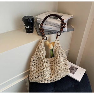 Detailed close-up of woven beige straw tote featuring artisanal wooden bead handles