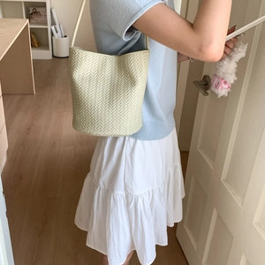 Detailed close-up of woven cream bucket bag showing intricate leather weaving craftsmanship