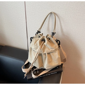 Detail of beige nylon drawstring bucket bag with pleated texture and canvas crossbody strap