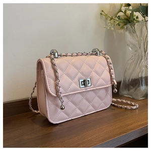 Close-up of pink quilted crossbody bag with silver twist lock and chain strap detail