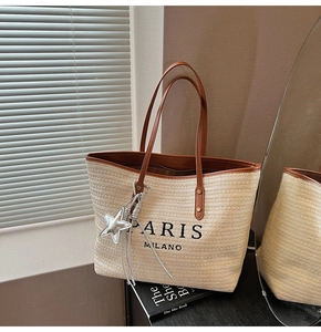 Close-up of woven tote bag with Paris Milano embroidery and silver star charm detail