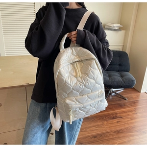 Detail of white quilted heart pattern on a puffy backpack with rope zipper pulls