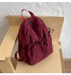 Macro detail of wine red nylon drawstring backpack with pleated texture and zipper