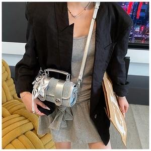 Mini sac à bandoulière en denim bleu clair porté avec une jupe grise et un blazer noir