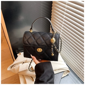 Detail of black quilted chain bag with gold sphere pendant and turn-lock closure