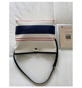 Macro shot of striped canvas bucket bag with toggle closure and black leather strap