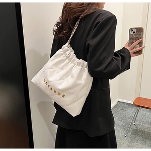 Close-up of white quilted chain bag with gold metal CLEAR K logo and drawstring details