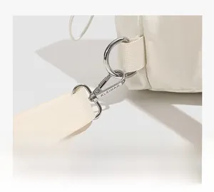 Détail du mousqueton en métal argenté et de l'anneau en D sur un sac en nylon beige