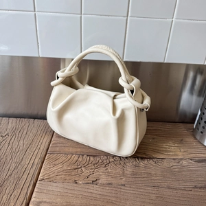 Detail of minimalist cream ruched cloud bag showing soft faux leather texture and knot handle