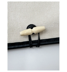Close-up of striped tote bag horn buckle and leather strap on canvas fabric