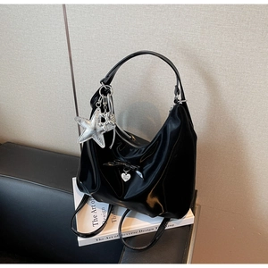 Detail of glossy black moon bag with silver star charm and bow on art books