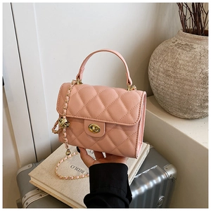 Detail of pink quilted crossbody bag with gold twist lock and chain strap on a vanity