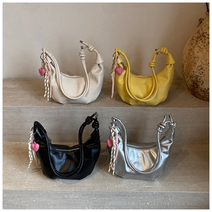 Detalle de bolsos bandolera de media luna en blanco, amarillo, negro y plata con nudos