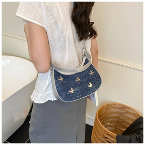 Dettaglio borsa a mezzaluna in denim blu con paillettes a farfalla e finiture argento