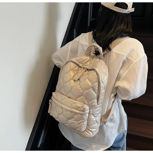 Detail of champagne quilted backpack with heart patterns and woven zipper pullers
