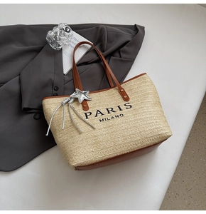 Detail of woven straw tote bag with brown leather trim and silver star charm
