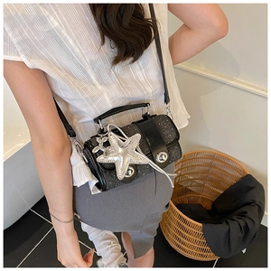 Détail du sac à main noir pailleté avec breloque étoile de mer et fermoir tournant