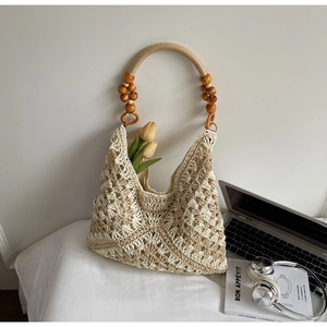 Detail of bohemian crochet tote with hollow pattern and wooden bead handle decoration