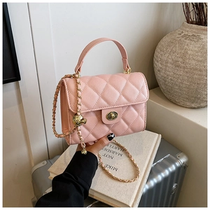 Detailed view of pink quilted handbag with gold hardware and chain strap in a lifestyle setting