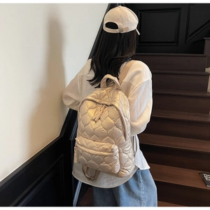Close-up of quilted diamond pattern and silk-like glossy fabric on a beige backpack