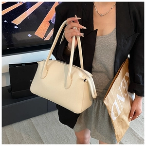 Dettaglio della borsa a mano beige con trama litchi e chiusura a cerniera in metallo