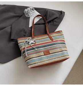 Detail of colorful woven tote bag with brown leather handles and a silver star charm