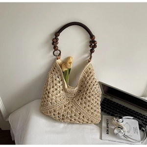 Detail of woven straw tote bag featuring dark brown wooden bead handles and hollow texture