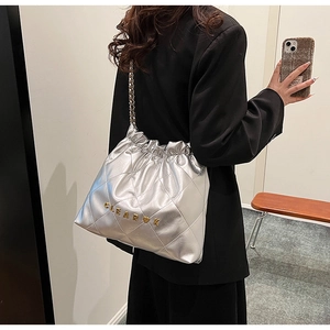 Detail of silver quilted drawstring bucket bag with gold metal letters and chain strap
