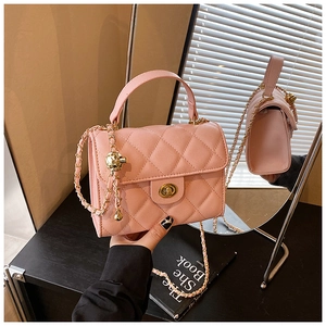 Detailed view of pink quilted handbag with gold chain strap and spherical charm ornament