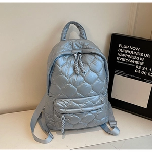 Detail of light blue quilted backpack with lattice embroidery and woven zipper pull