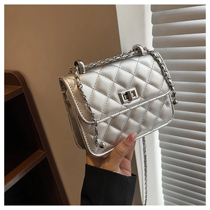 Close-up of silver quilted crossbody bag featuring metal turn-lock and chain strap