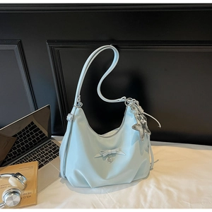 Detail of light blue crossbody bag with bow, heart pendant and silver star charm decor
