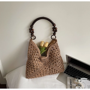 Detail of hand-woven straw tote with wooden bead handles and hollow crochet design