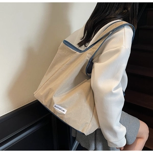 Detail der großen beige Tote Bag mit blauem Kontrastrand und Markenlabel an der Schulter