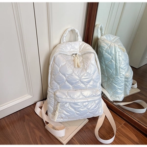Detailed view of white heart-quilted backpack with glossy finish and top handle design