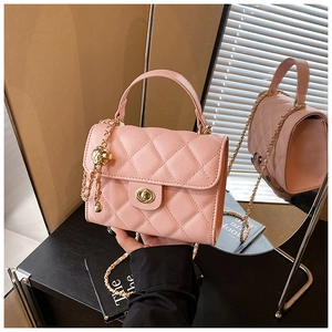 Detail of pink quilted leather crossbody bag with gold chain and ball charm