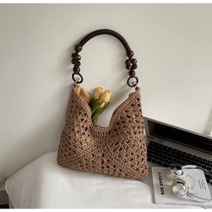 Detail of hollow woven tote bag with wooden beads and round handle on desk