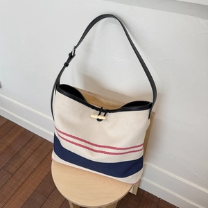 Close-up of canvas tote bag featuring red and blue stripes with a wooden horn button
