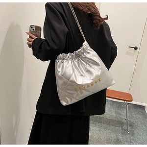 Detail of silver quilted bucket bag with chain strap shown on model in home setting