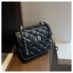 Macro detail of black quilted leather texture and silver metallic twist lock on flap bag
