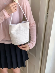 White woven bucket shoulder bag featuring a classic herringbone texture and slim strap