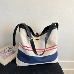 Detail of nautical striped canvas tote with adjustable leather straps and toggle closure