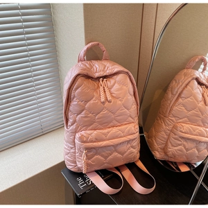 Detailed view of pink quilted heart patterns on soft fabric backpack with zipper cords