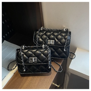 Detail of black quilted chain bags with silver twist locks on wooden surface