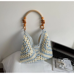 Close-up of woven tote bag featuring blue geometric patterns and natural wood bead handles