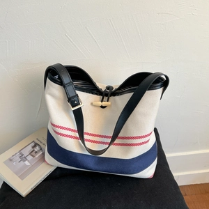 Detail of canvas tote bag with red and blue stripes and a wooden toggle closure
