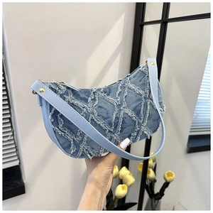 Sac bandoulière en denim bleu clair avec texture frangée et sangle à clous dorés