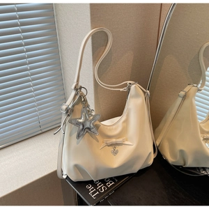 Detailed close-up of cream leather shoulder bag with bow and silver star charm